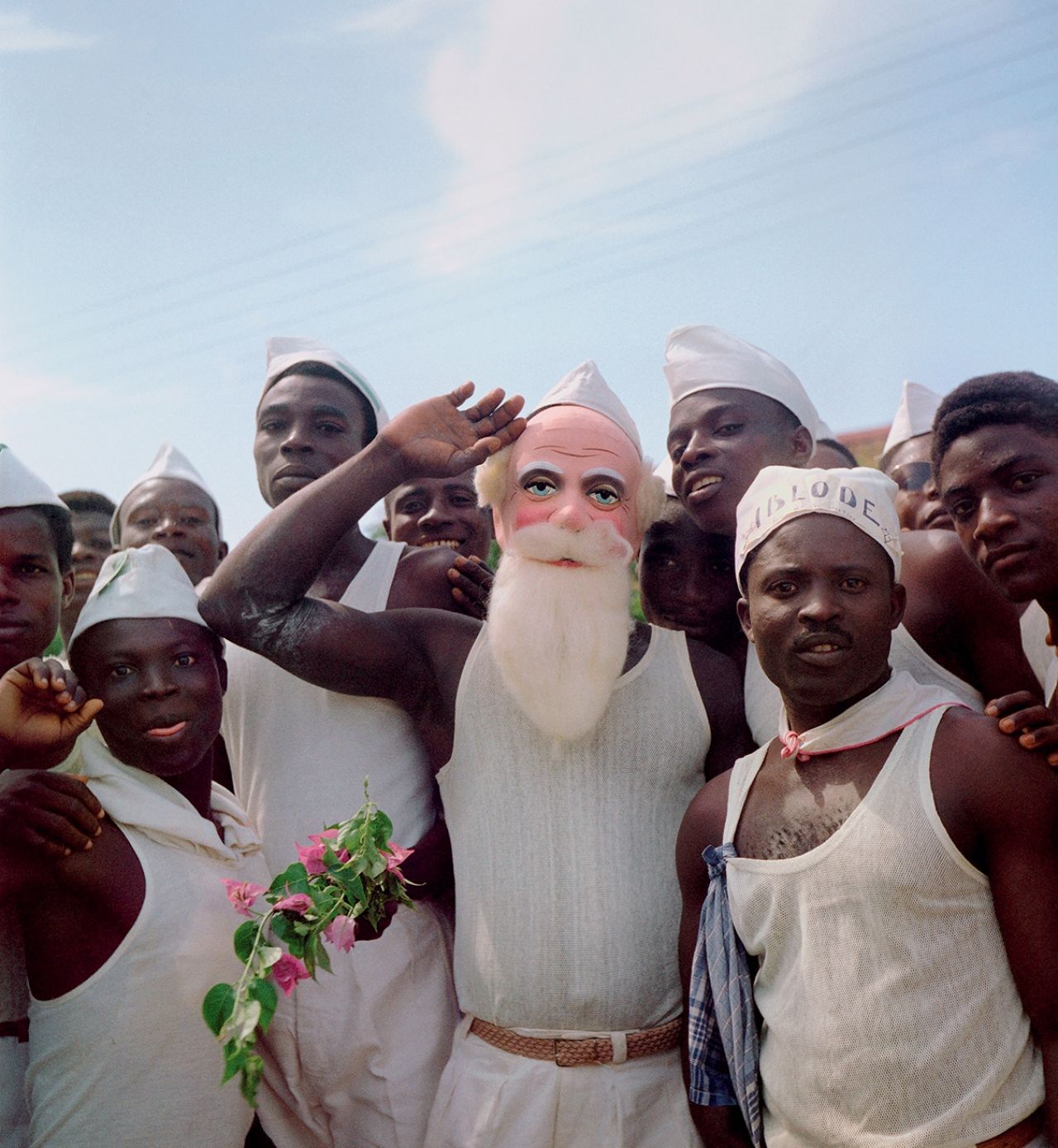 Togoland (Togo), 1958 – Group of men with white hats, one with the slogan “Ablode” (freedom), and another with a Santa Claus mask on election day, April 27 © 2021 Todd Webb Archive