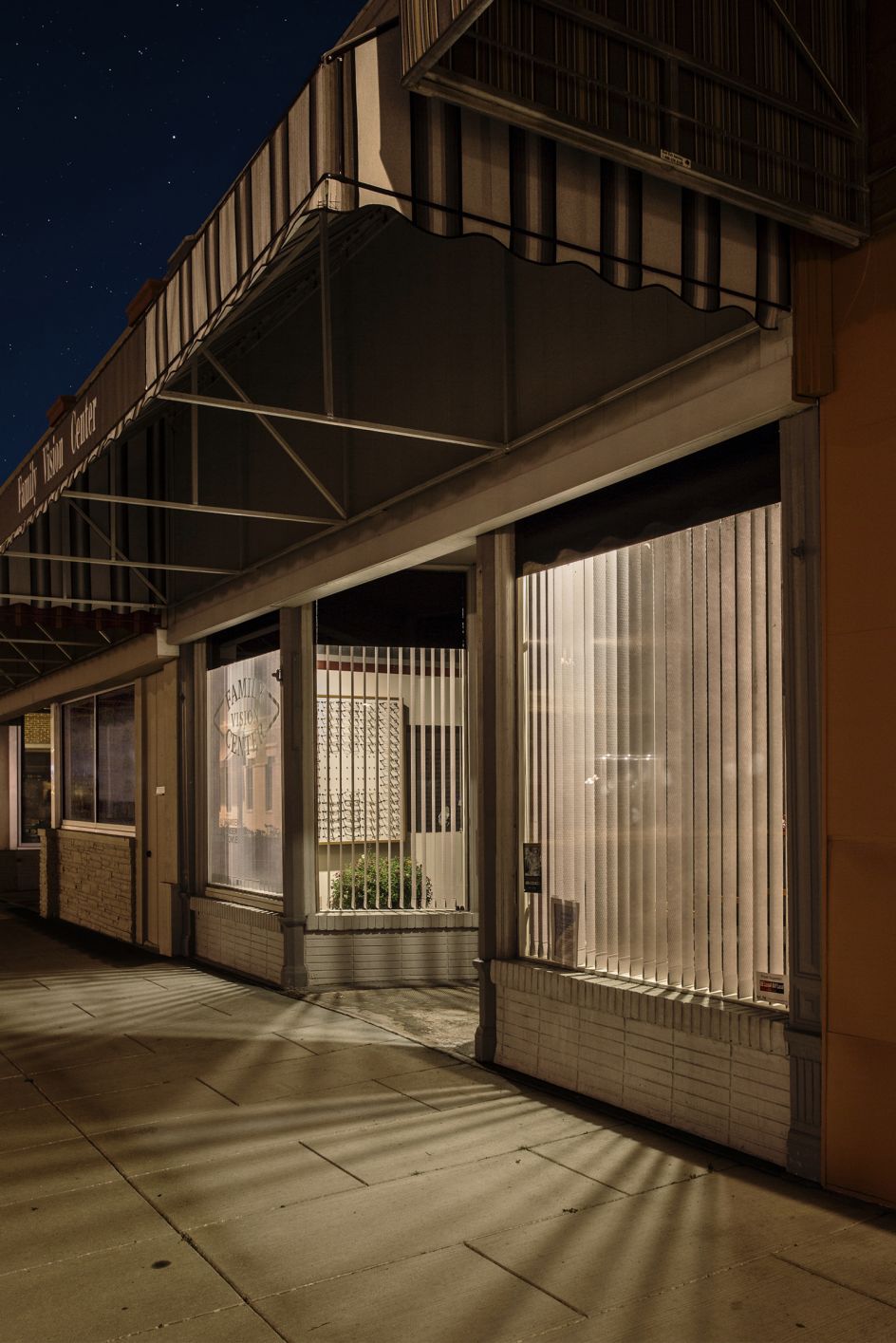 The lights of shop windows call out to the passer by at night in a silent and almost introvert desperation, attempting to entice potential customers for the following day’s opening hours.