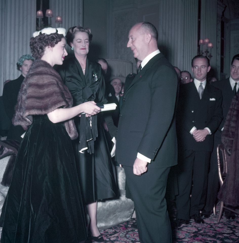 Princess Margaret (left), with the Duchess of Marlborough behind, presents Christian Dior with a scroll entitling him to Honorary Life Membership of the British Red Cross after the presentation of his Winter Collection at Blenheim Palace on 3rd November 1954. © Popperfoto / Getty Images