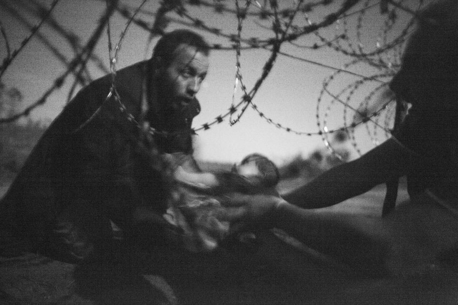 World Press Photo of the Year: A man passes a baby through the fence at the Hungarian-Serbian border in Röszke, Hungary, 28 August 2015. Warren Richardson.