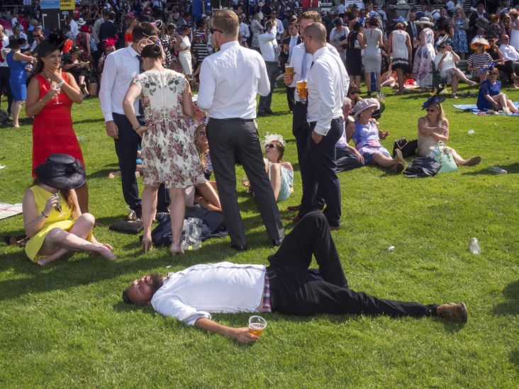 A man with his pint rests on the grass at Royal Ascot. June 2017. All photography courtesy of Peter Dench. © Peter Dench
