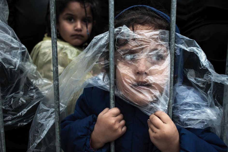 People, first prize singles: A child is covered with a raincoat while she waits in line to register at a refugee camp in Preševo, Serbia. Matic Zorman.