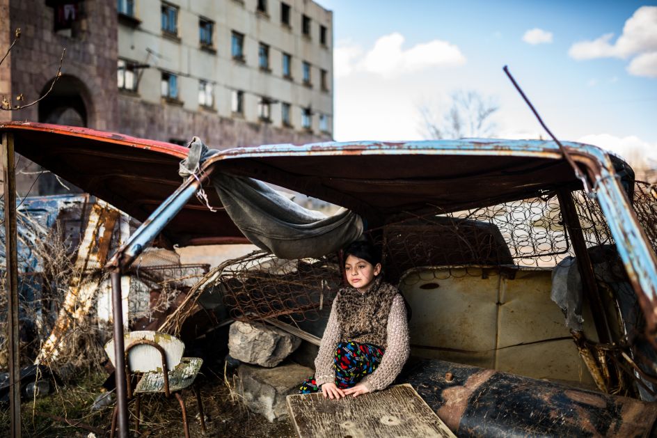 Syuzanna (9) sitting in a “shelter” made of old car rusty parts in front of the abandoned building she lives in Gyumri, Armenia. Ten days ago Syuzanna's father committed suicide, as people say, because of the debts | © Yulia Grigoryants, Armenia, Shortlist, Professional, Daily Life, 2017 Sony World Photography Awards