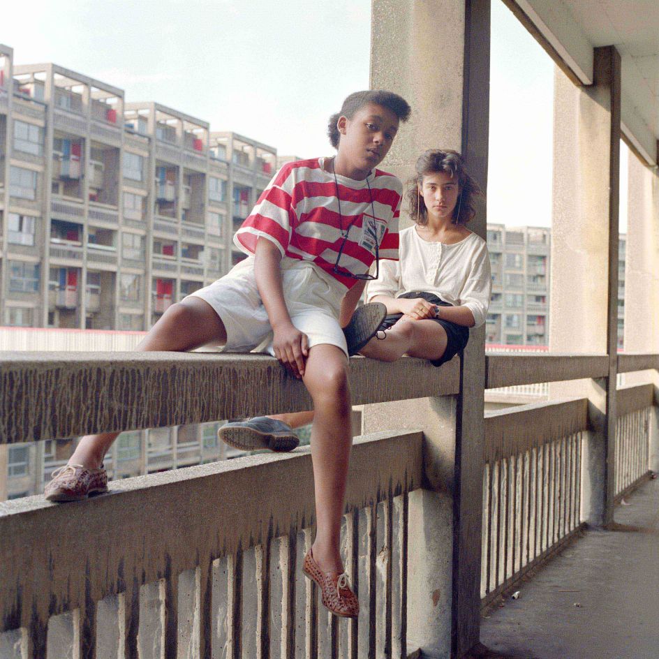Bill Stephenson, Donna Hargreaves and Carmen Bello sit on an unguarded fourth storey concrete parapet. Hyde Park Flats, Sheffield, 1988 © Bill Stephenson