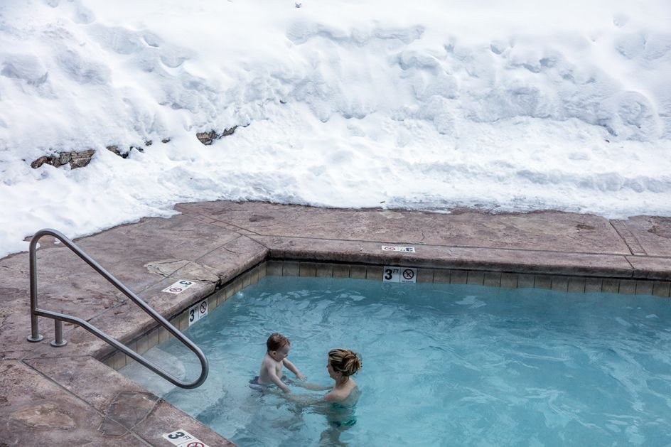 Dudley Williams of Denver and her son, Dag, get a dip that is both warm and briskly chilling in a hotel pool in Vail, Colorado. The pool is toasty warm; the surrounding air temperature is well below freezing. Vail, a town in Eagle County's Vail Pass, did not exist until four years after the founding of the Vail Ski Resort in 1962. As of 2015, Vail Mountain, just 1.5 hours from Denver, was Colorado's largest ski mountain. [Note to researchers: Dudley is the correct name of the mom.] ©Library of congress