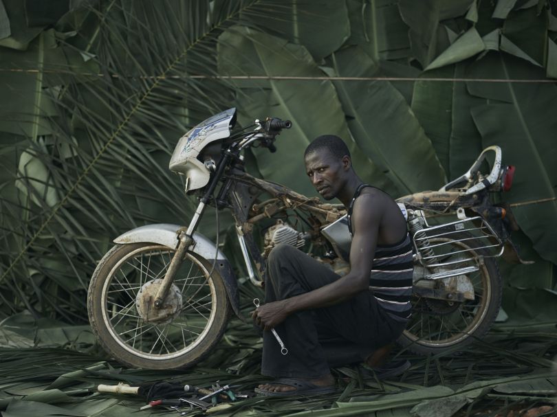 Kempah Ginnah, 42, youth leader and mechanic with his own motorbike, in the village of Tombohuaun. Because he has a bike, he is asked to give people lifts to the health centre. Kailahun District, Sierra Leone, May 2017. WaterAid/ Joey Lawrence