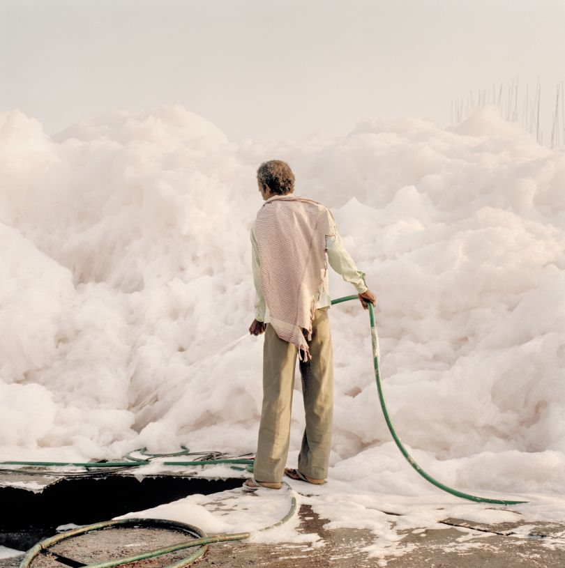 A worker with a water hose tries to tame an iceberg of foam created by the chemical waste dumped by the factories along the Yamuna river, Delhi, 2015 © Giulio Di Sturco