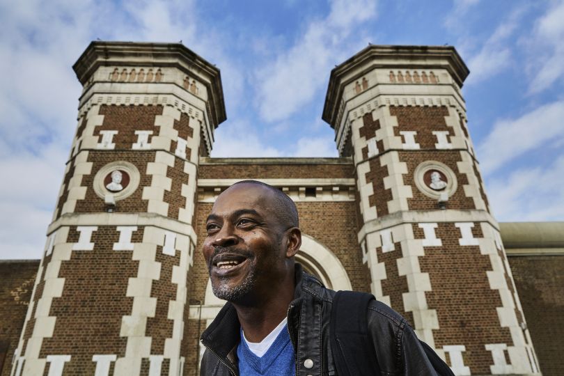 Stephen Akpabio-Klementowski, Open University staff member, graduate and former prison who studied for his degree during a 16 year sentence, pictured here outside Wormwood Scrubs Prison, features in The OU’s new collection by renowned photographer Chris Floyd, released today to mark the University’s 50th Anniversary