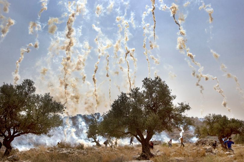 Israeli soldiers shoot tear gas during a demonstration against Israel's controversial separation barrier in the West Bank village of Nilin. © Cris Toala Olivares / De Beeldunie. Documentary Single Image Winner, Magnum and LensCulture Photography Awards 2016