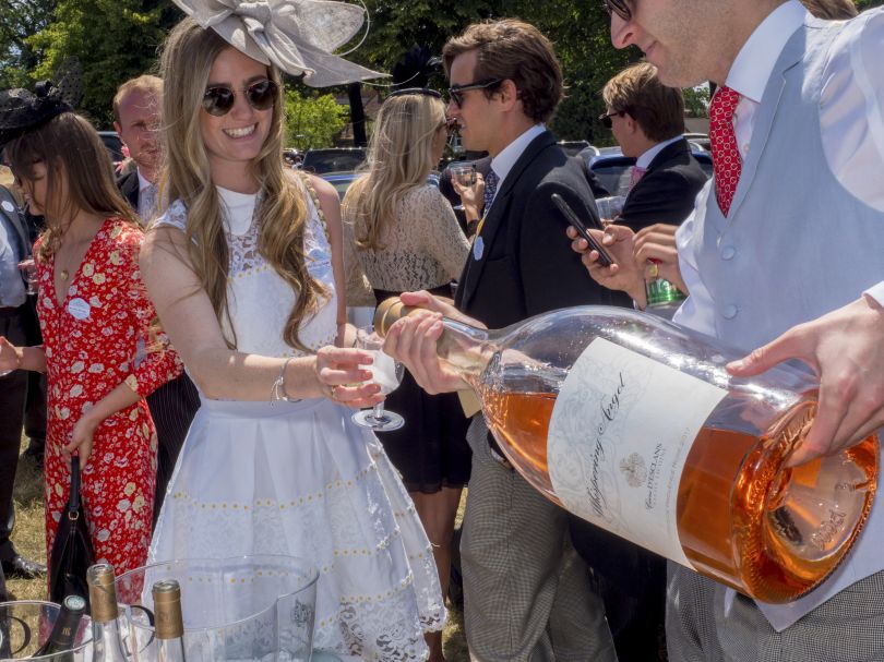 A giant bottle of rosé wine is poured for a guest at a picnic at the Royal Enclosure's Car Park One on Ladies Day at Royal Ascot. June 2018 © Peter Dench