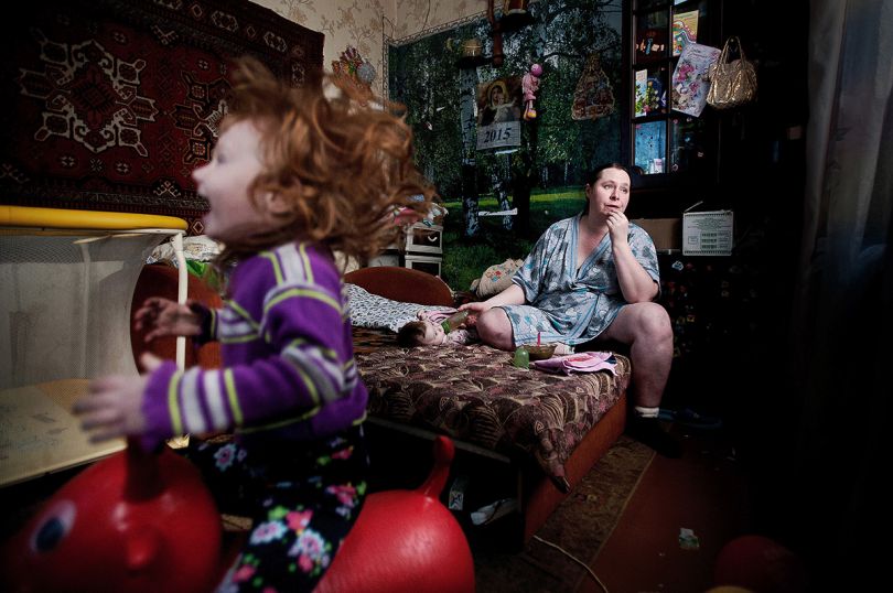 Local Family - Anton Unitsyn: Oksana and her two kids. Over 50% of their small salary is spent for utilities. They own this little room in the old house. Girl with ginger hair - Sothia, was born with heart disease. (Professional Daily Life)