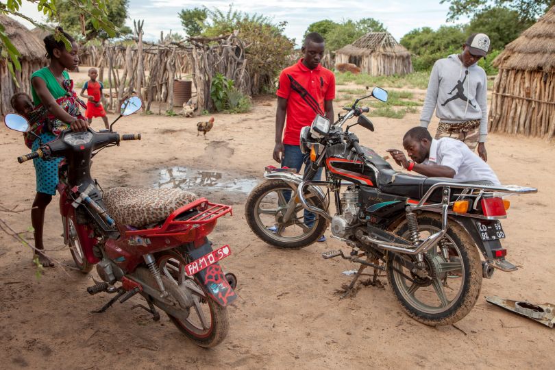 Some guys repairing their motorbikes in front of their “Kimbo” where they live, south Angola