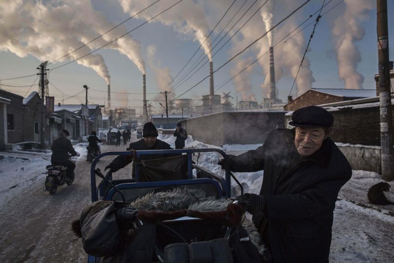 Daily Life, first prize singles: Chinese men pull a tricycle in a neighborhood next to a coal-fired power plant in Shanxi, China. Kevin Frayer.