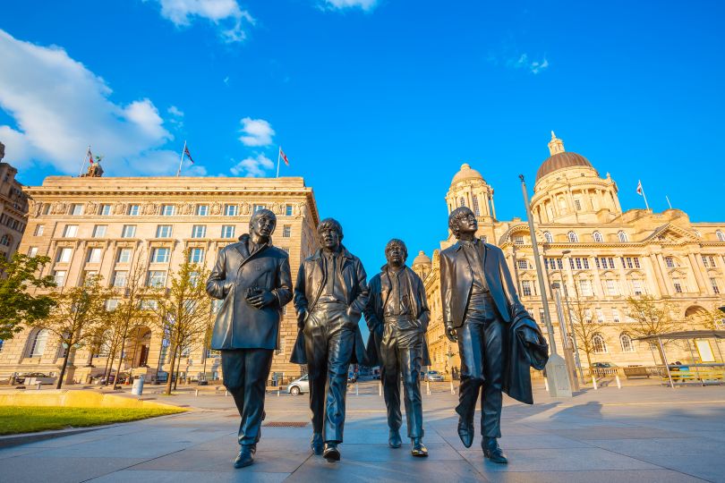 Bronze statue of the Beatles stands at the Pier Head on the side of River Mersey, sculpted by Andrew Edwards. Image licensed via Adobe Stock / By Coward Lion