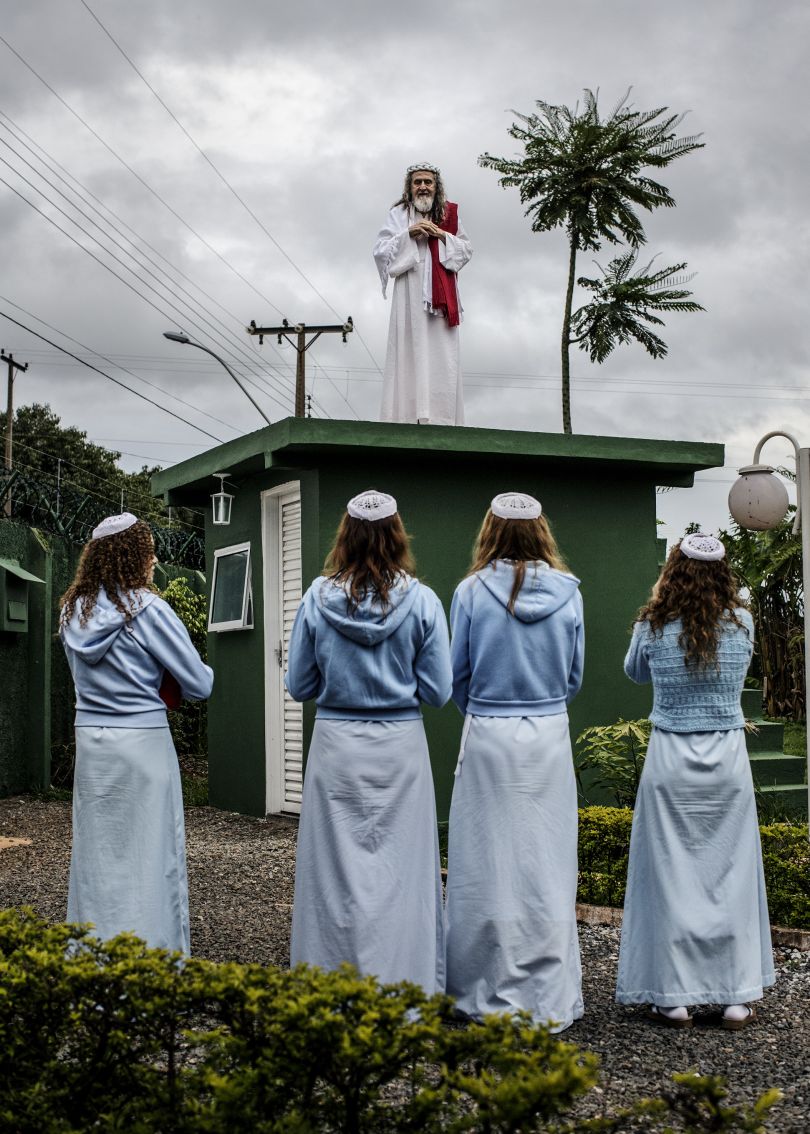 INRI Cristo preaches to his followers from the top of the compound guardhouse. The disciples live a quiet and secluded life inside the compound, growing most of their own food and focussing on INRI's mission. Brazil, 2014 | © Jonas Bendiksen/ Magnum Photos