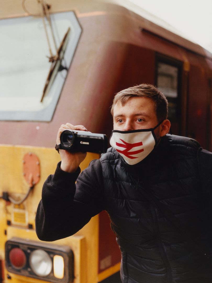 Young trainspotter proudly wears a National Rail facemask, London Victoria © Freddie Miller