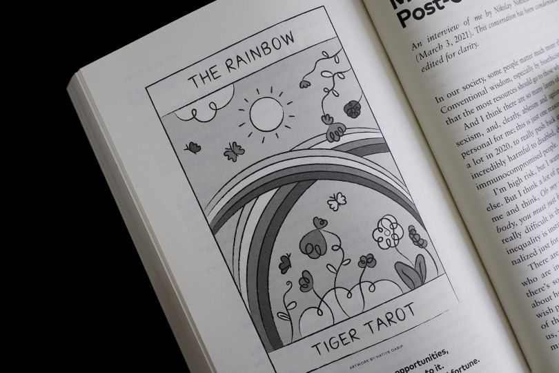 A photo from the ‘Year of the Tiger’ book, with a black and white illustration on the left page. In the illustration, the double rainbows are welcoming the flowers and the sun. Four butterflies are flying around, enjoying the good atmosphere and happiness that the rainbows brought.