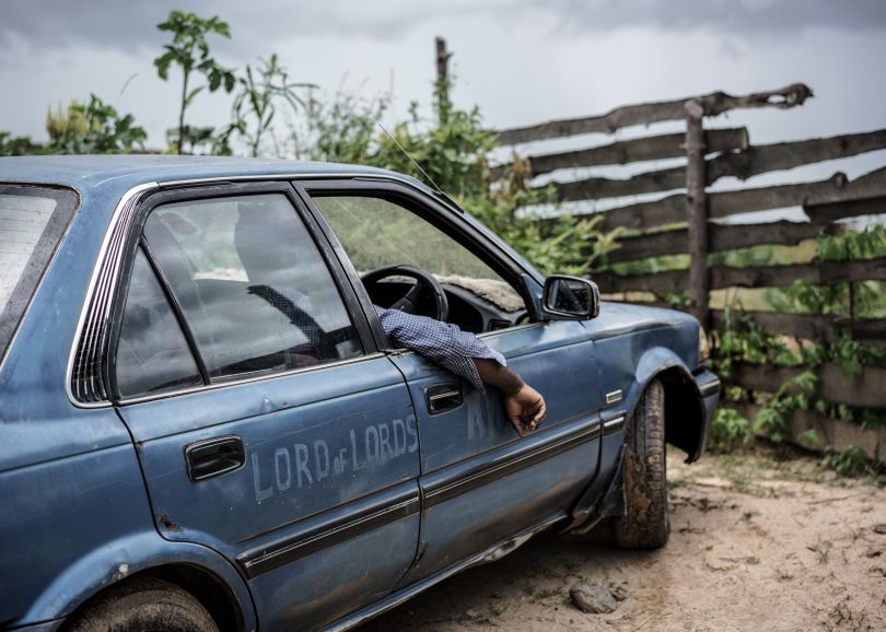 Much like the biblical Jesus was originally a carpenter, Jesus of Kitwe makes a living as a taxi driver. Here he sits in one of his two Toyota Corollas. Zambia, 2015 | © Jonas Bendiksen/ Magnum Photos