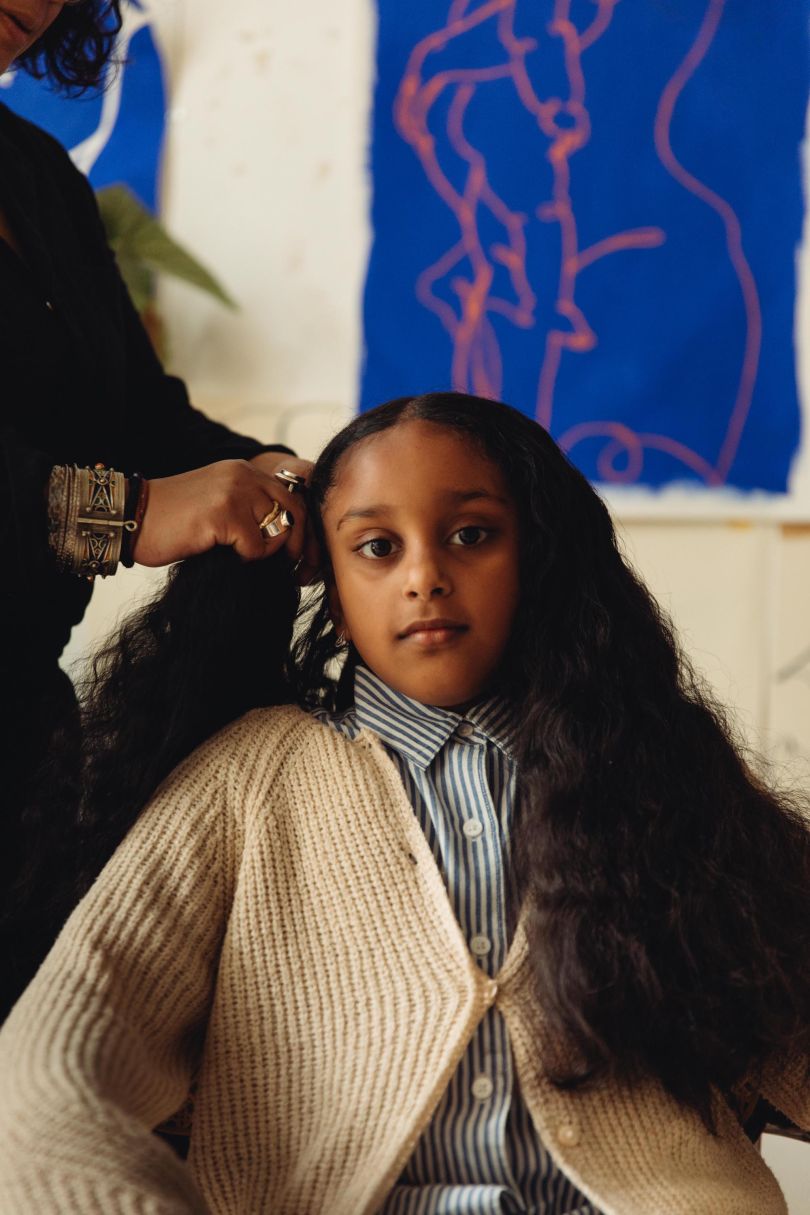 Laxmi Hussain braid's her daughter's hair at her studio